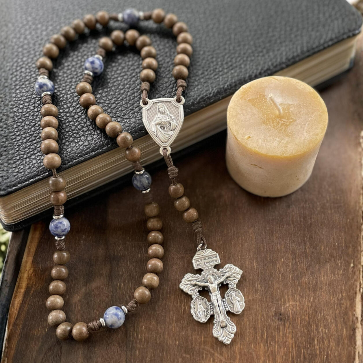 A handmade Seven Sorrows Rosary made from paracord with a silver Pardon Crucifix and silver Immaculate Heart of Mary centerpiece and the Hail Mary beads are grey brown wood and the Our Father beads are blue stone.