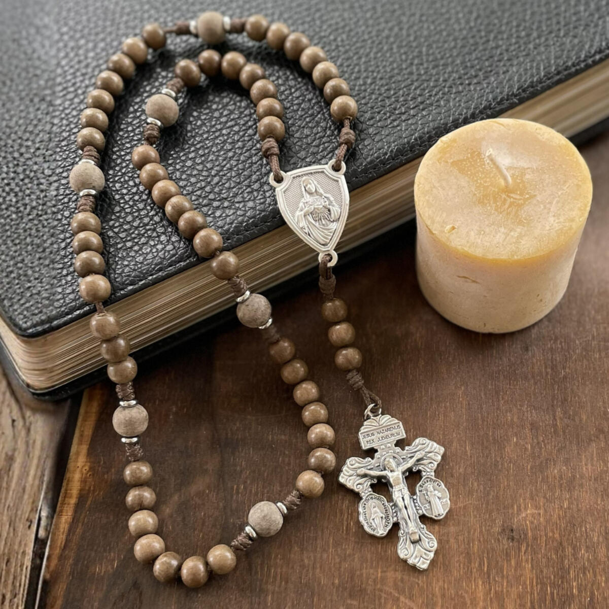 A handmade Seven Sorrows Rosary made from paracord with a silver Pardon Crucifix and silver Immaculate Heart of Mary centerpiece and the Hail Mary beads are grey brown wood and the Our Father beads are unfinished grey wood.