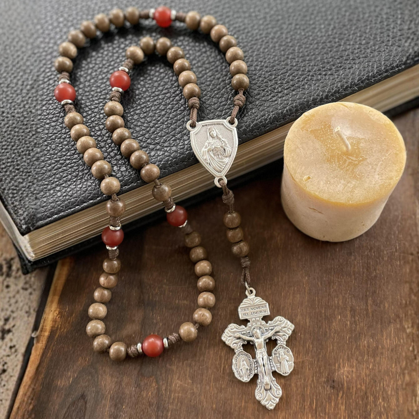 A handmade Seven Sorrows Rosary made from paracord with a silver Pardon Crucifix and silver Immaculate Heart of Mary centerpiece and the Hail Mary beads are grey brown wood and the Our Father beads are red stone.