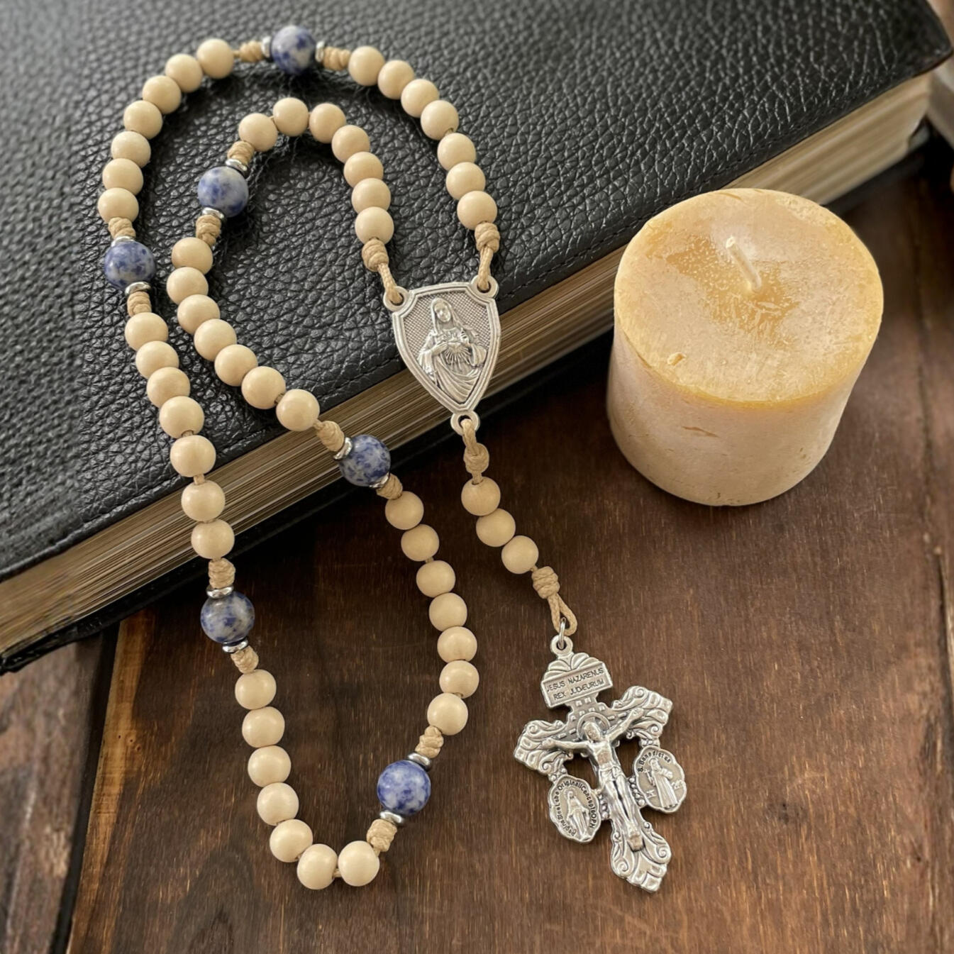 A handmade Seven Sorrows Rosary made from paracord with a silver Pardon Crucifix and silver Immaculate Heart of Mary centerpiece and the Hail Mary beads are cream color wood and the Our Father beads are blue stone.